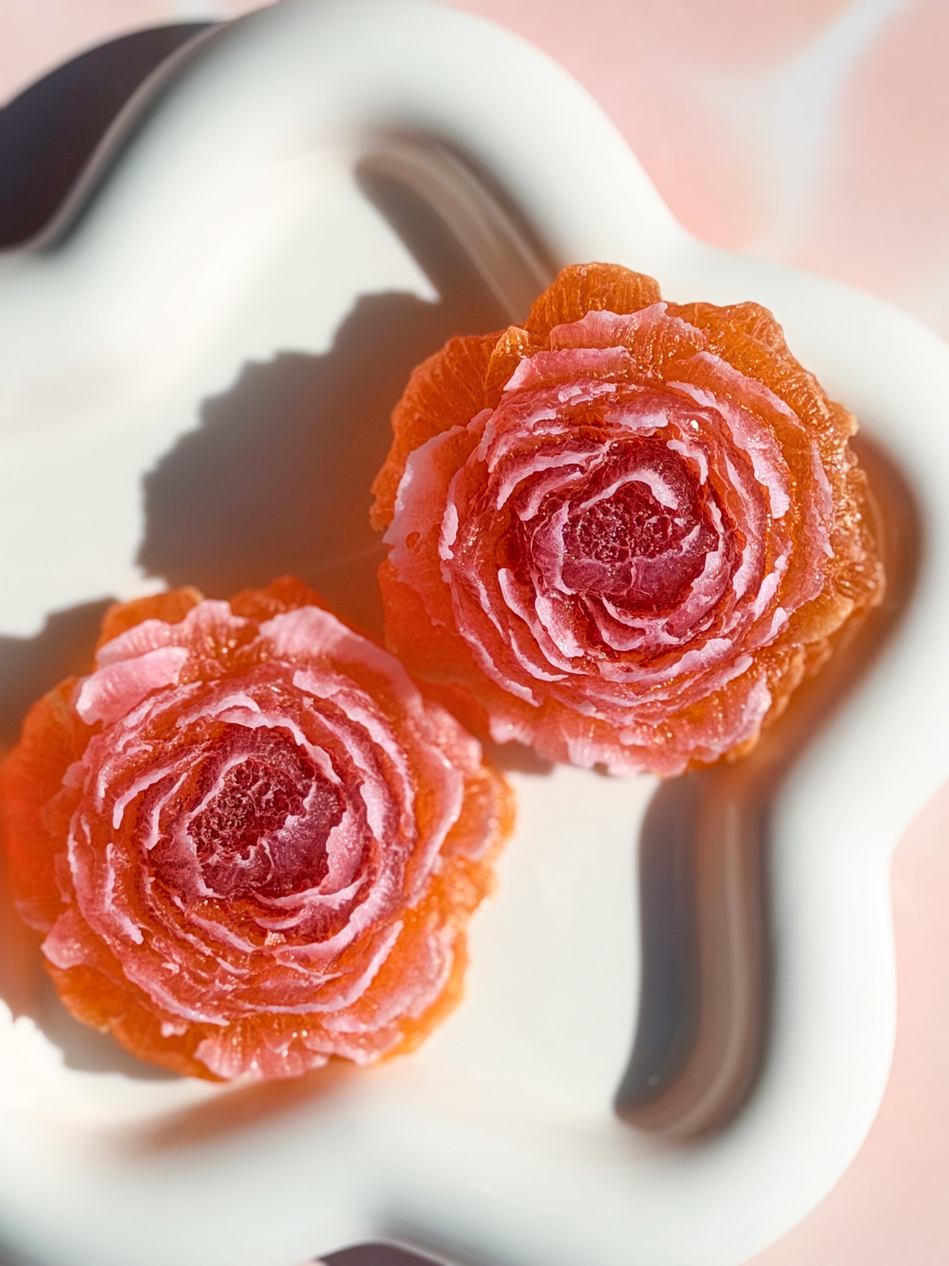 Two red rose-shaped candies on a white plate with a blurred background